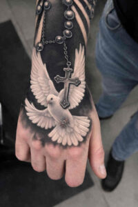 Black and grey tattoo on the hand featuring a white dove with open wings and a rosary with a hanging cross; AI-generated idea, perfect for a cover-up.