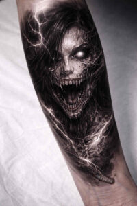 Demon face tattoo design on forearm in black and grey realism; AI-generated project idea, cover-up ready.