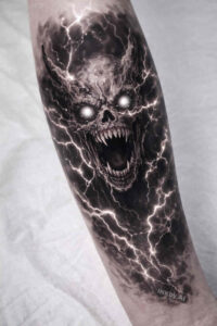 Black and grey tattoo design idea: a demon skull surrounded by lightning and dark shadows, rendered as a concept sketch; ideal for cover-up.