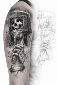 Forearm tattoo in black and grey showing a skull inside a small square box held by skeletal fingers; a project idea, cover-up suitable.