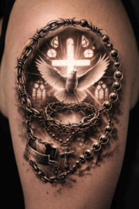Cross with surrounding rosary beads forming a circular loop and chain details in black and grey realism; project idea, cover-up ready.
